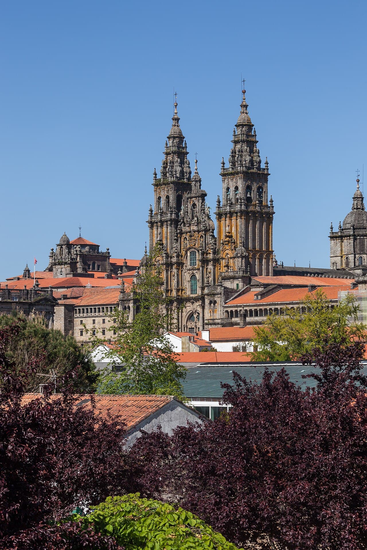 Towers of the Cathedral of Santiago de Compostela rising above rooftops and trees, seen from the Alameda.